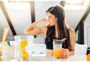 Female showing her bicep muscle while holding a protein shake